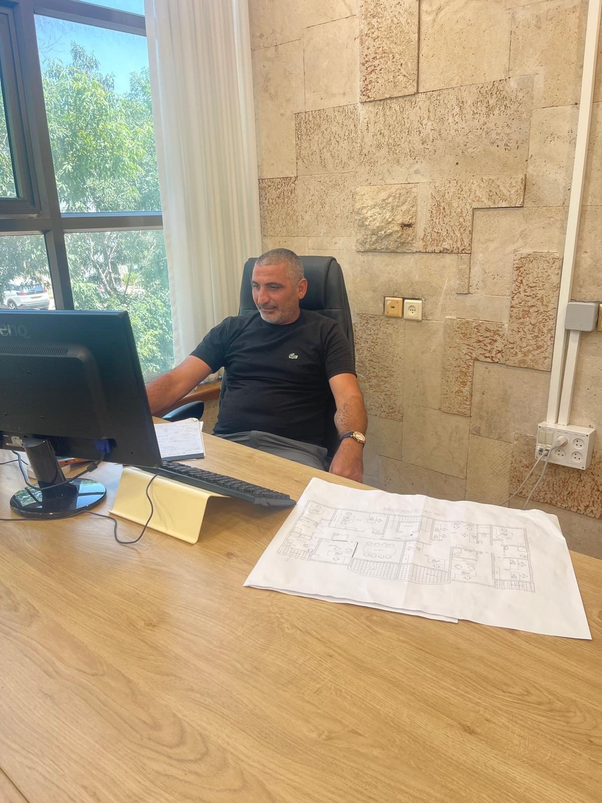 אמל דאגר בודק תוכניות בנייה במשרד